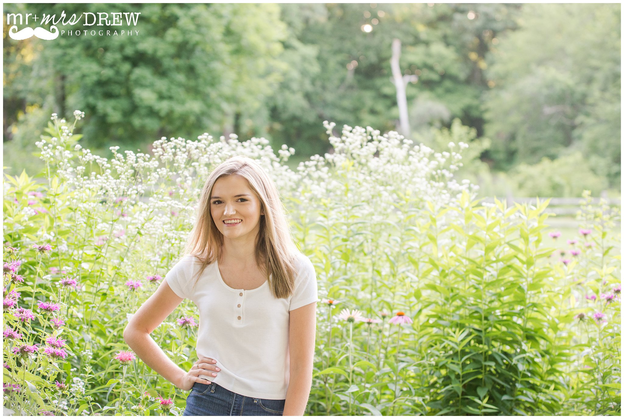 Senior Portrait of girl in white t-shirt surrounded by white flowers. 