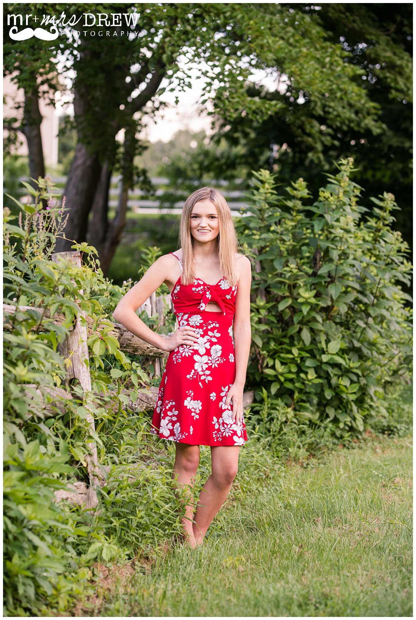 Senior Portrait of girl in Red floral dress hand on her hip.