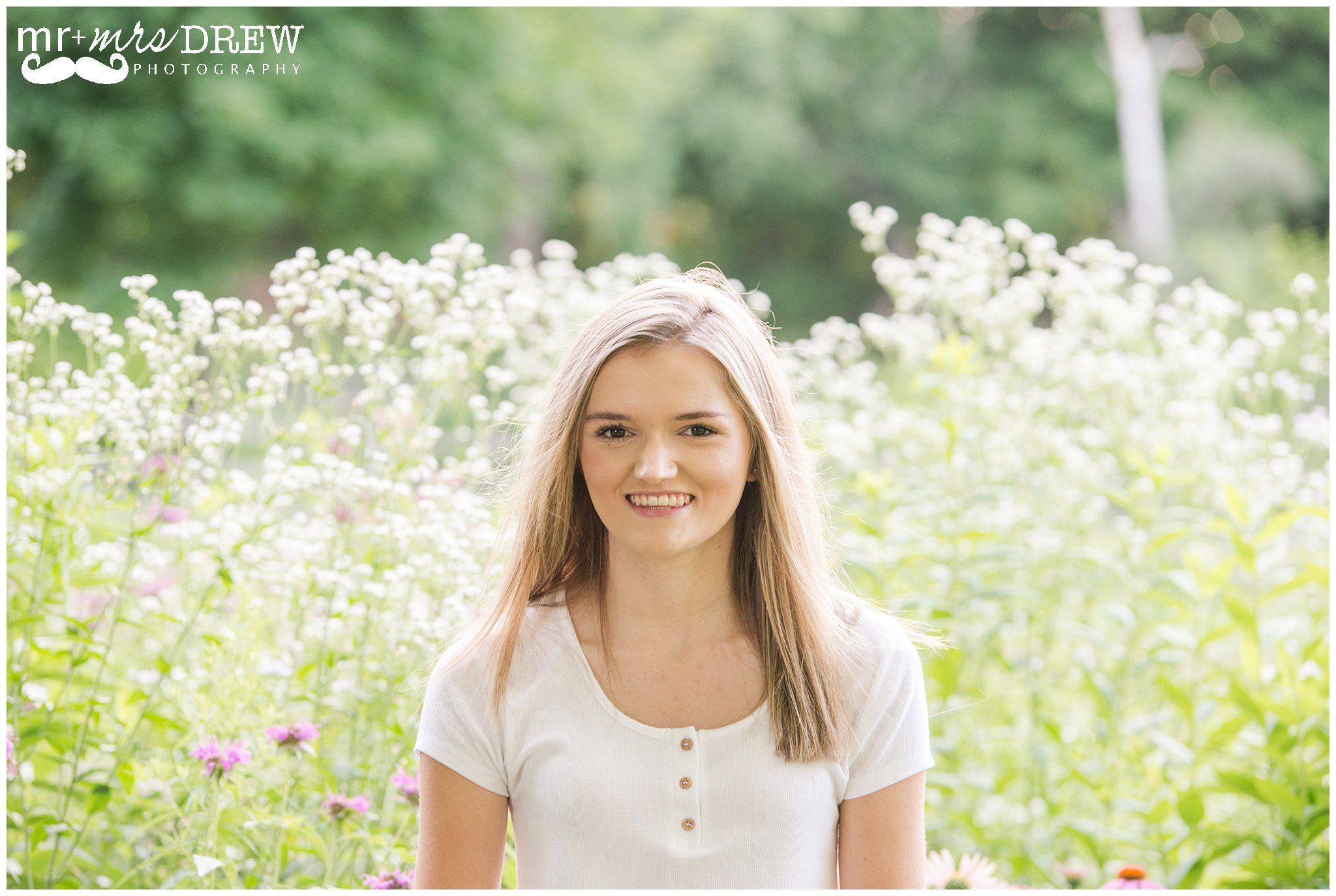 Senior Portrait of girl in white t-shirt surrounded by white flowers. 